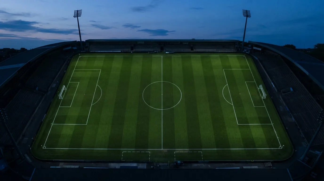 Ein Fußballplatz am Abend aus der Vogelperspektive, Flutlichtmasten ausgeschaltet, die Rasenlinien deutlich sichtbar.